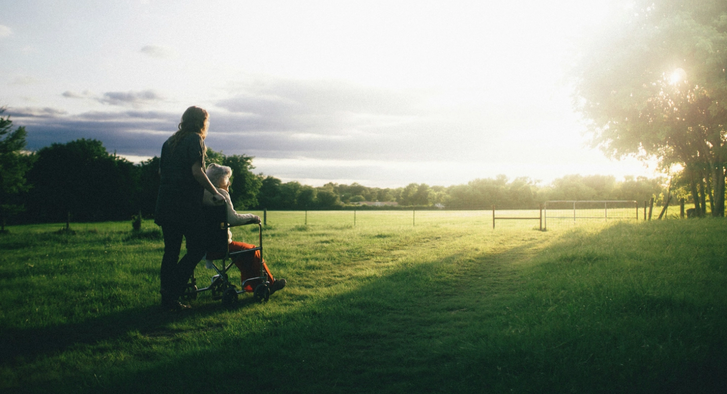 Woman being pushed in a wheelchair by a caregiver